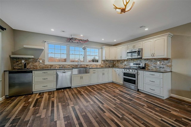 kitchen featuring appliances with stainless steel finishes, dark hardwood / wood-style flooring, tasteful backsplash, and sink