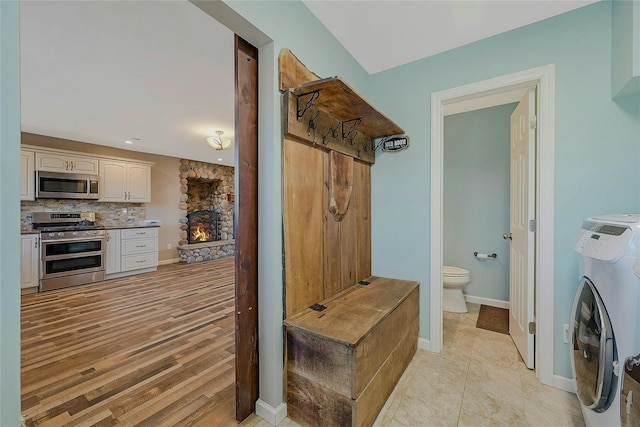 mudroom with a stone fireplace and washing machine and clothes dryer