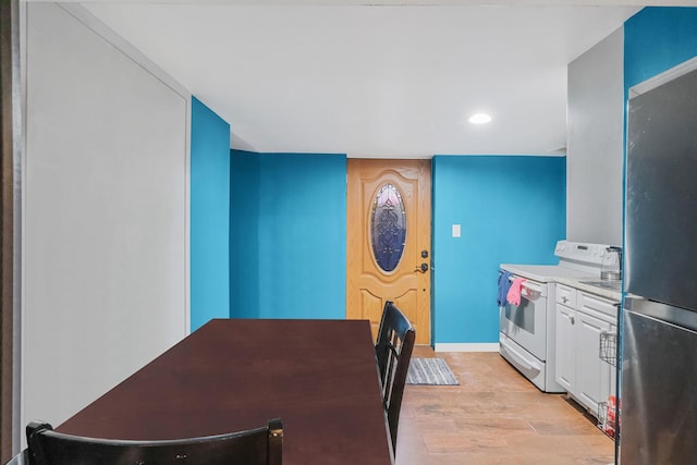 kitchen featuring stainless steel refrigerator, white cabinetry, white electric range, and light hardwood / wood-style floors