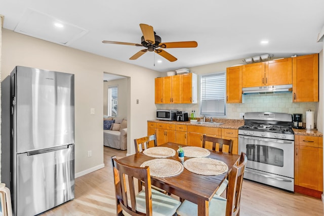 kitchen featuring sink, light hardwood / wood-style flooring, decorative backsplash, light stone countertops, and stainless steel appliances