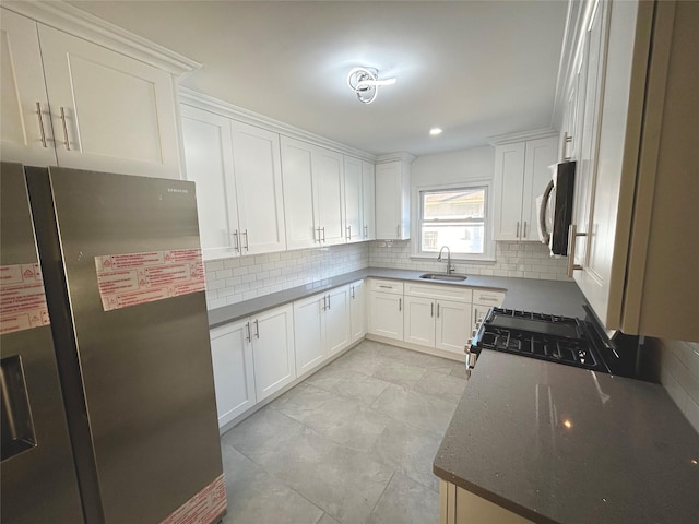 kitchen featuring backsplash, white cabinetry, appliances with stainless steel finishes, dark stone countertops, and sink