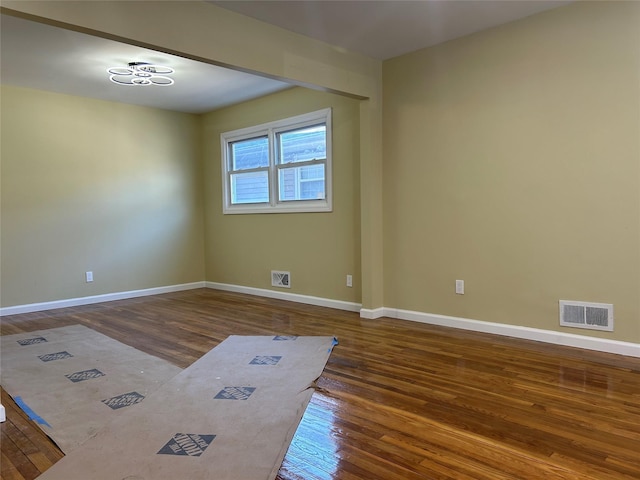 empty room featuring visible vents, baseboards, and wood finished floors