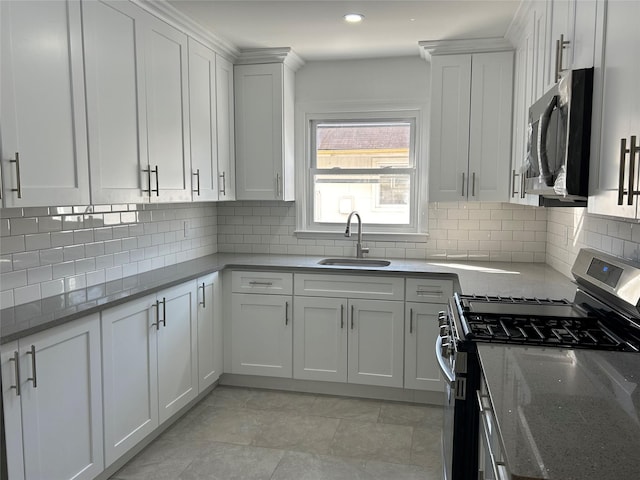 kitchen with white cabinets, decorative backsplash, light stone counters, stainless steel appliances, and a sink