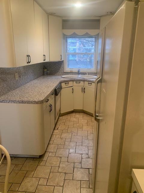 kitchen with white cabinetry, dishwasher, sink, and white refrigerator