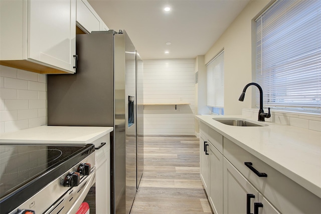 kitchen featuring white cabinets, sink, decorative backsplash, light hardwood / wood-style floors, and stainless steel appliances