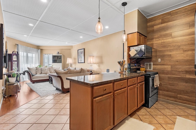 kitchen featuring stainless steel electric range oven, decorative light fixtures, light tile patterned flooring, and wood walls