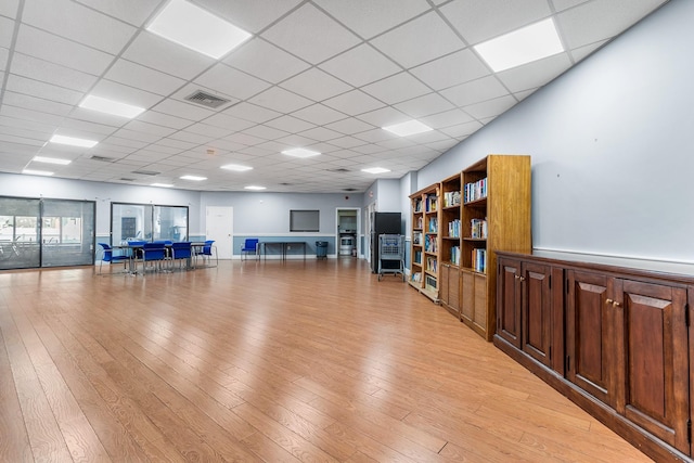 exercise room featuring light hardwood / wood-style flooring and a paneled ceiling