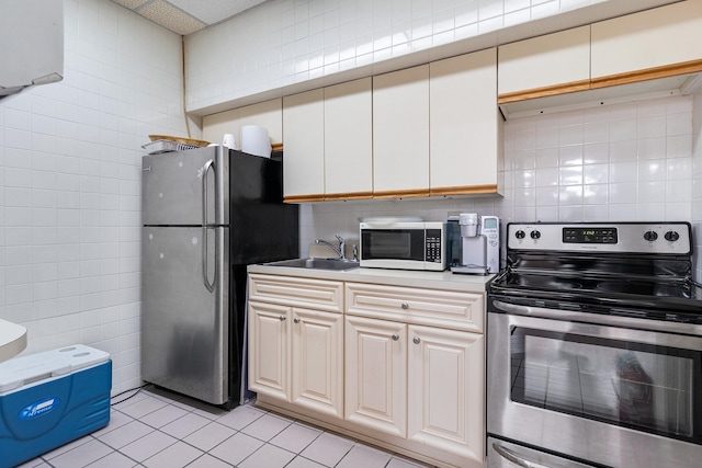 kitchen featuring sink, tile walls, stainless steel appliances, tasteful backsplash, and light tile patterned flooring