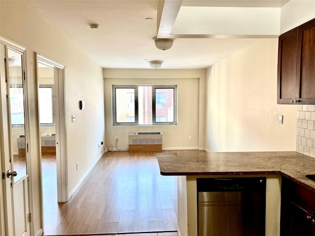 kitchen featuring decorative backsplash, dark brown cabinetry, an AC wall unit, and light hardwood / wood-style flooring