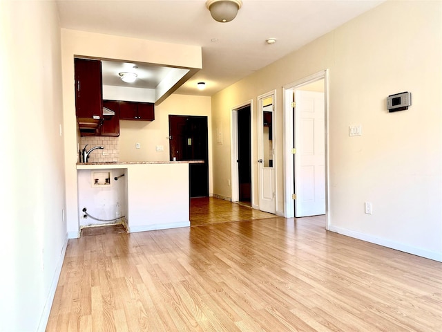 kitchen featuring kitchen peninsula, hardwood / wood-style floors, tasteful backsplash, and sink