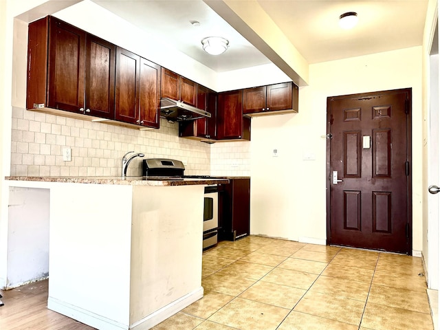 kitchen with light stone countertops, stainless steel range, sink, backsplash, and light tile patterned floors