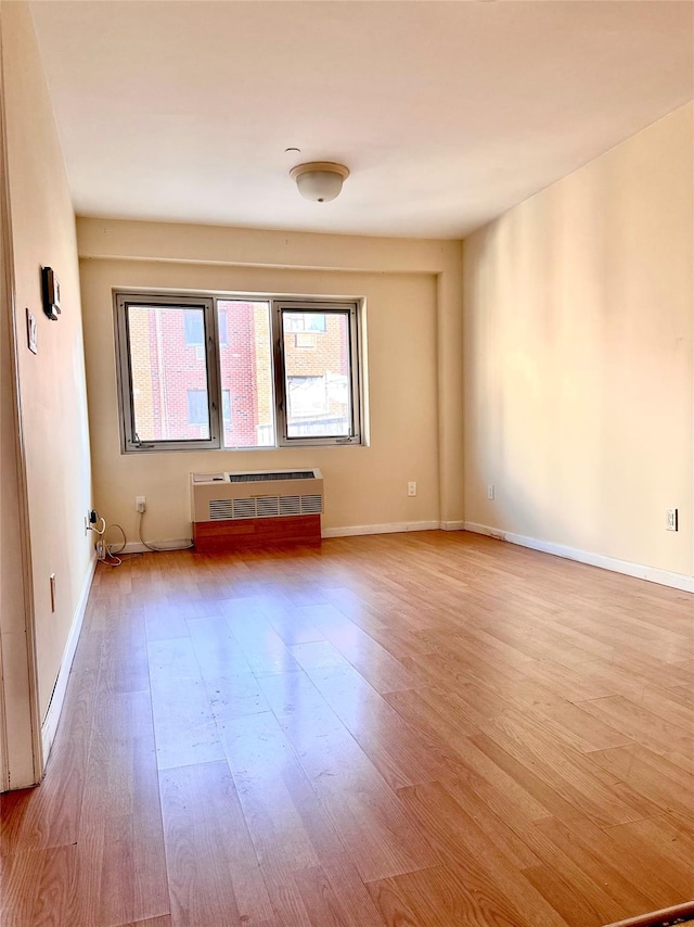 empty room featuring radiator heating unit and light hardwood / wood-style flooring