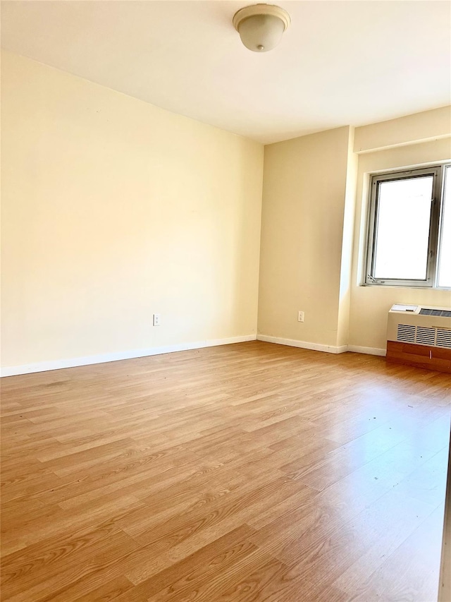 spare room with a wall mounted AC and light hardwood / wood-style floors