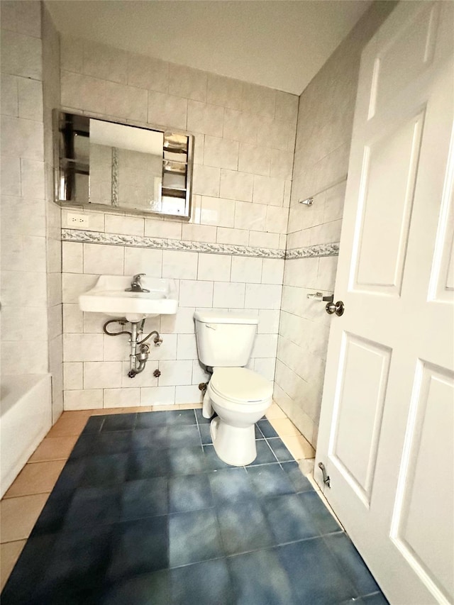 bathroom featuring sink, tile patterned floors, toilet, a bathtub, and tile walls