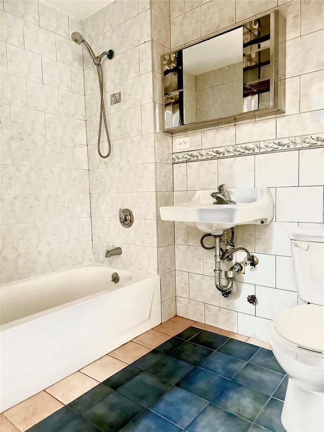 bathroom with toilet, tile patterned floors, and tile walls