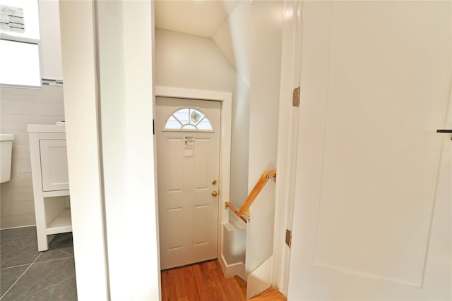 entryway with dark tile patterned floors and tile walls