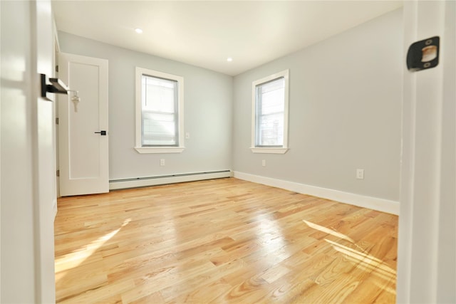 spare room featuring a wealth of natural light, a baseboard radiator, and light wood-type flooring