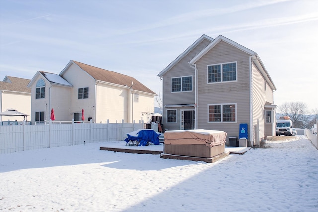 snow covered rear of property featuring a hot tub