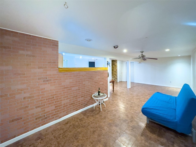 unfurnished room with ceiling fan and brick wall