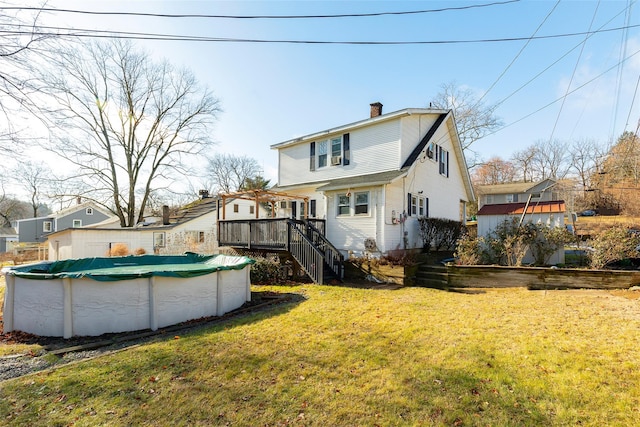 rear view of property with a lawn and a pool side deck