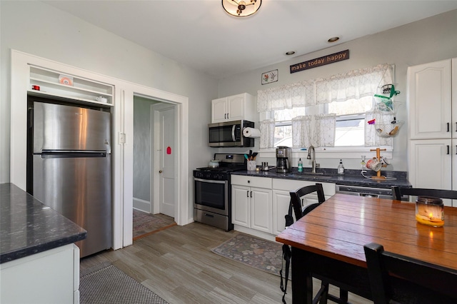 kitchen featuring white cabinetry, sink, light wood-type flooring, and appliances with stainless steel finishes