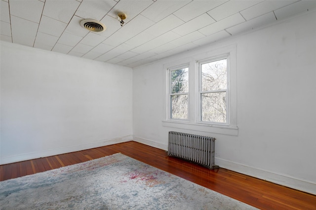 spare room featuring radiator heating unit and dark hardwood / wood-style floors