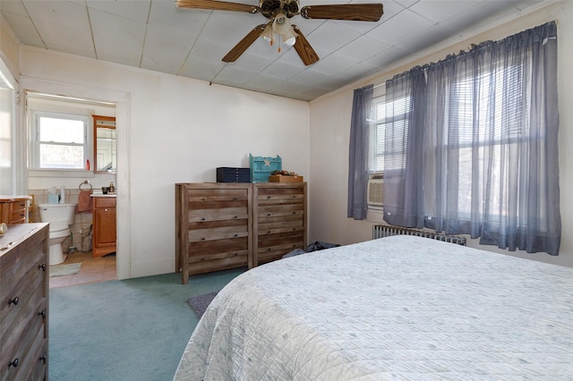 carpeted bedroom featuring radiator heating unit, connected bathroom, and ceiling fan