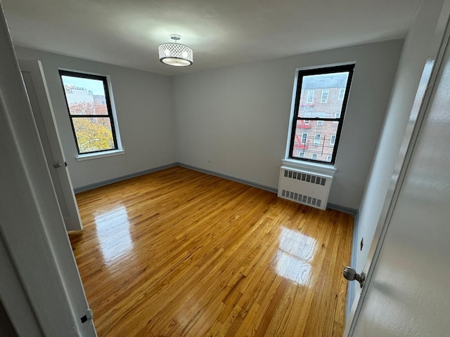 unfurnished room with light hardwood / wood-style floors and radiator heating unit