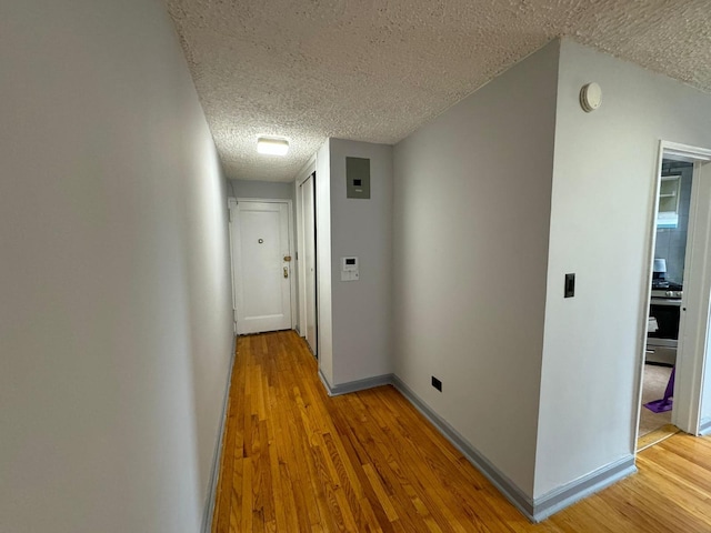 corridor with light hardwood / wood-style floors and a textured ceiling