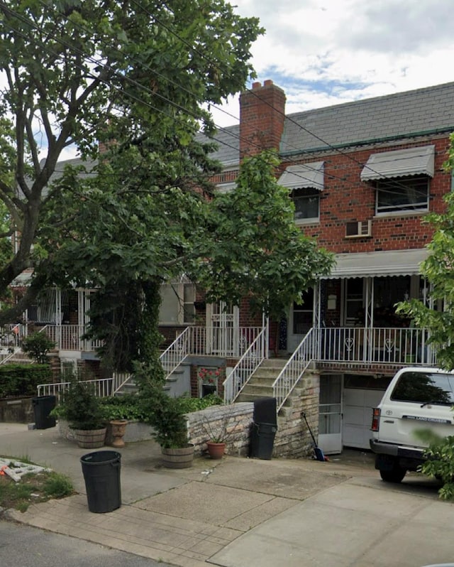 view of property with brick siding, driveway, and stairs