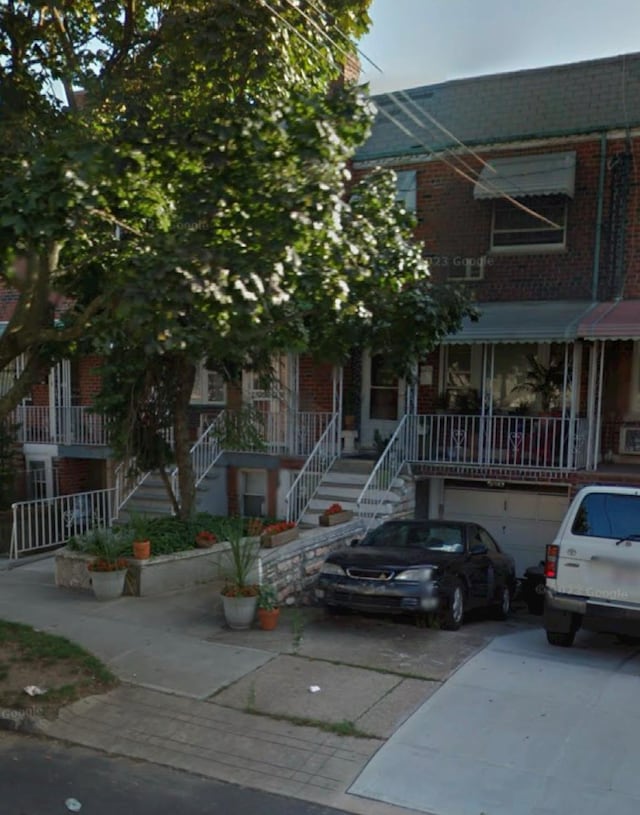 townhome / multi-family property featuring stairs, driveway, and brick siding