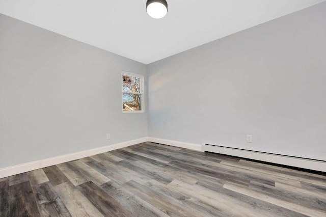 unfurnished room with hardwood / wood-style floors and a baseboard heating unit