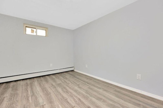 unfurnished room featuring baseboard heating and light hardwood / wood-style flooring