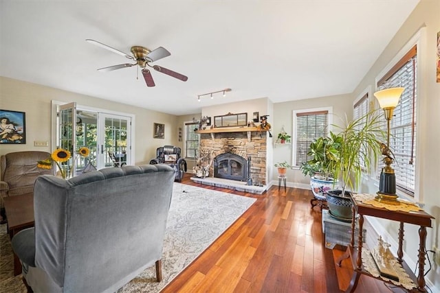 living room with a fireplace, wood-type flooring, french doors, and ceiling fan