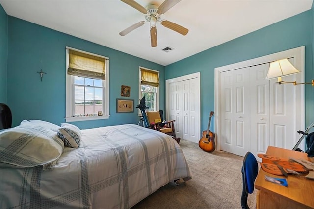 bedroom with carpet flooring, two closets, and ceiling fan