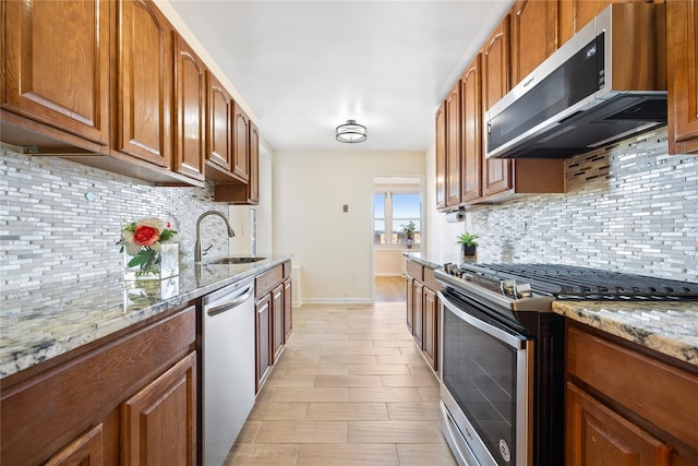 kitchen featuring tasteful backsplash, light stone counters, sink, and stainless steel appliances