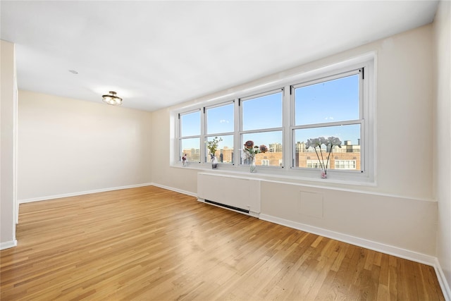 empty room with radiator heating unit and light wood-type flooring