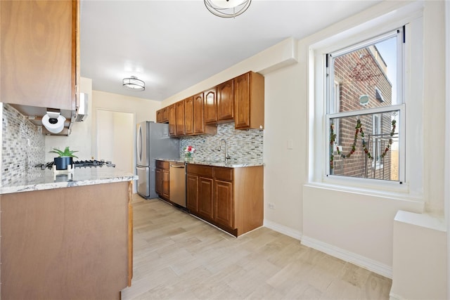 kitchen featuring a wealth of natural light, tasteful backsplash, light stone counters, and stainless steel appliances