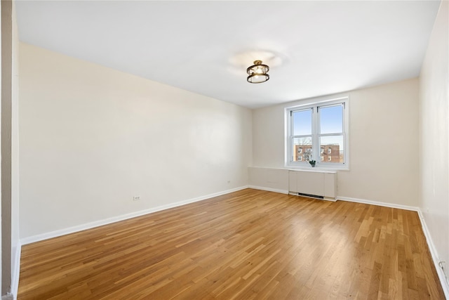 unfurnished room featuring hardwood / wood-style flooring and radiator