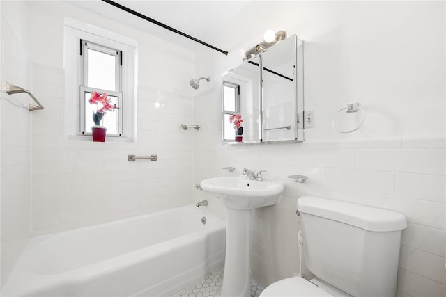 full bathroom with plenty of natural light, tiled shower / bath, tile walls, and toilet