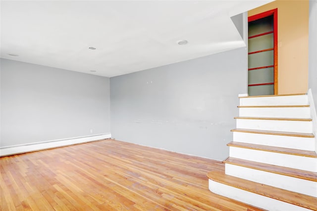 stairs featuring baseboard heating and hardwood / wood-style flooring