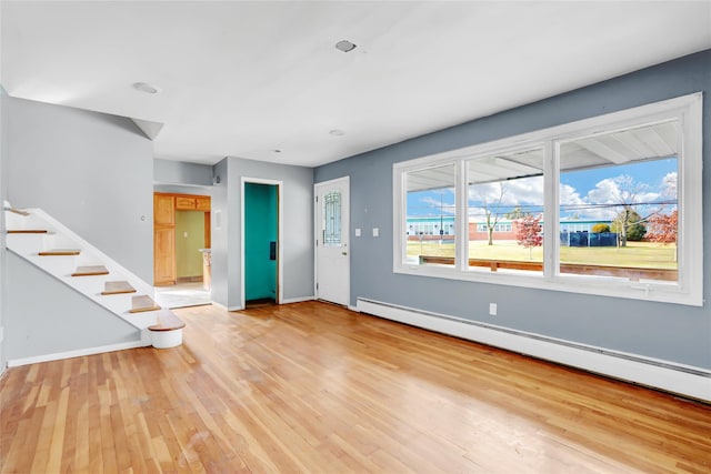 unfurnished living room with a healthy amount of sunlight, light hardwood / wood-style floors, and a baseboard heating unit