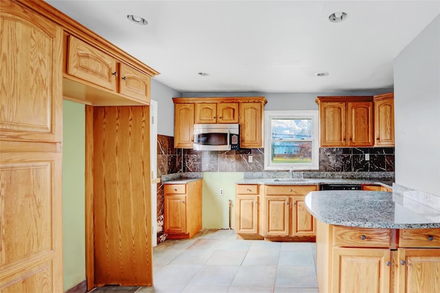 kitchen with light stone countertops, light tile patterned floors, tasteful backsplash, and sink