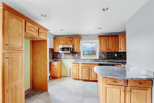 kitchen featuring light stone countertops, decorative backsplash, light tile patterned floors, and sink