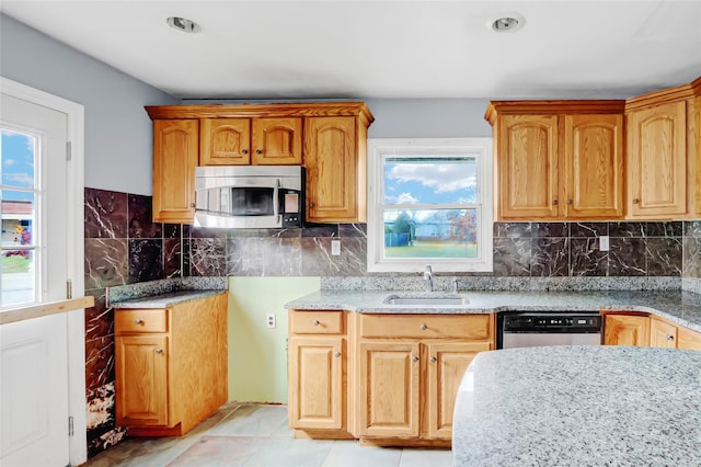 kitchen with light tile patterned floors, stainless steel appliances, light stone counters, and sink