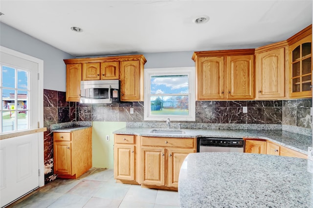 kitchen featuring light stone counters, sink, decorative backsplash, and stainless steel appliances