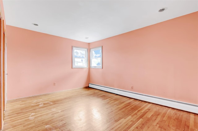 empty room with light wood-type flooring and a baseboard radiator