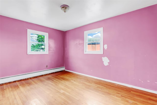 unfurnished room featuring a baseboard heating unit and light wood-type flooring