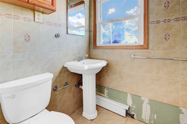 bathroom featuring tile patterned floors, toilet, tile walls, and a baseboard heating unit