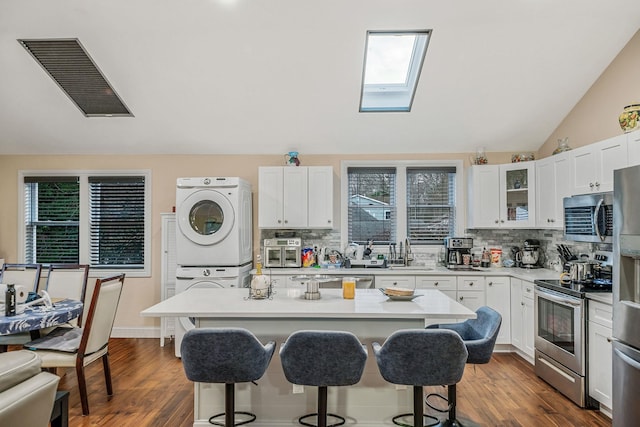 kitchen featuring white cabinetry, a center island, sink, stacked washer / drying machine, and appliances with stainless steel finishes